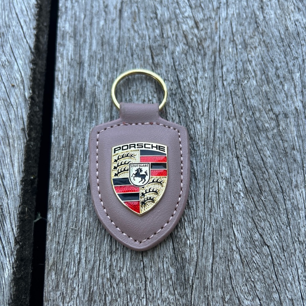 Porsche crest keyring with gold, red, and red crest on leather fob.